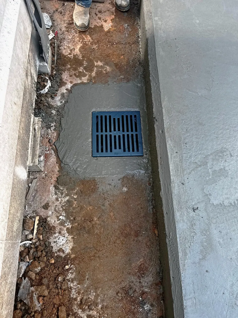 New floor drain set in the concrete beside the pad